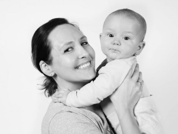 Black and white studio portrait of a mother holding her baby, both looking towards the camera